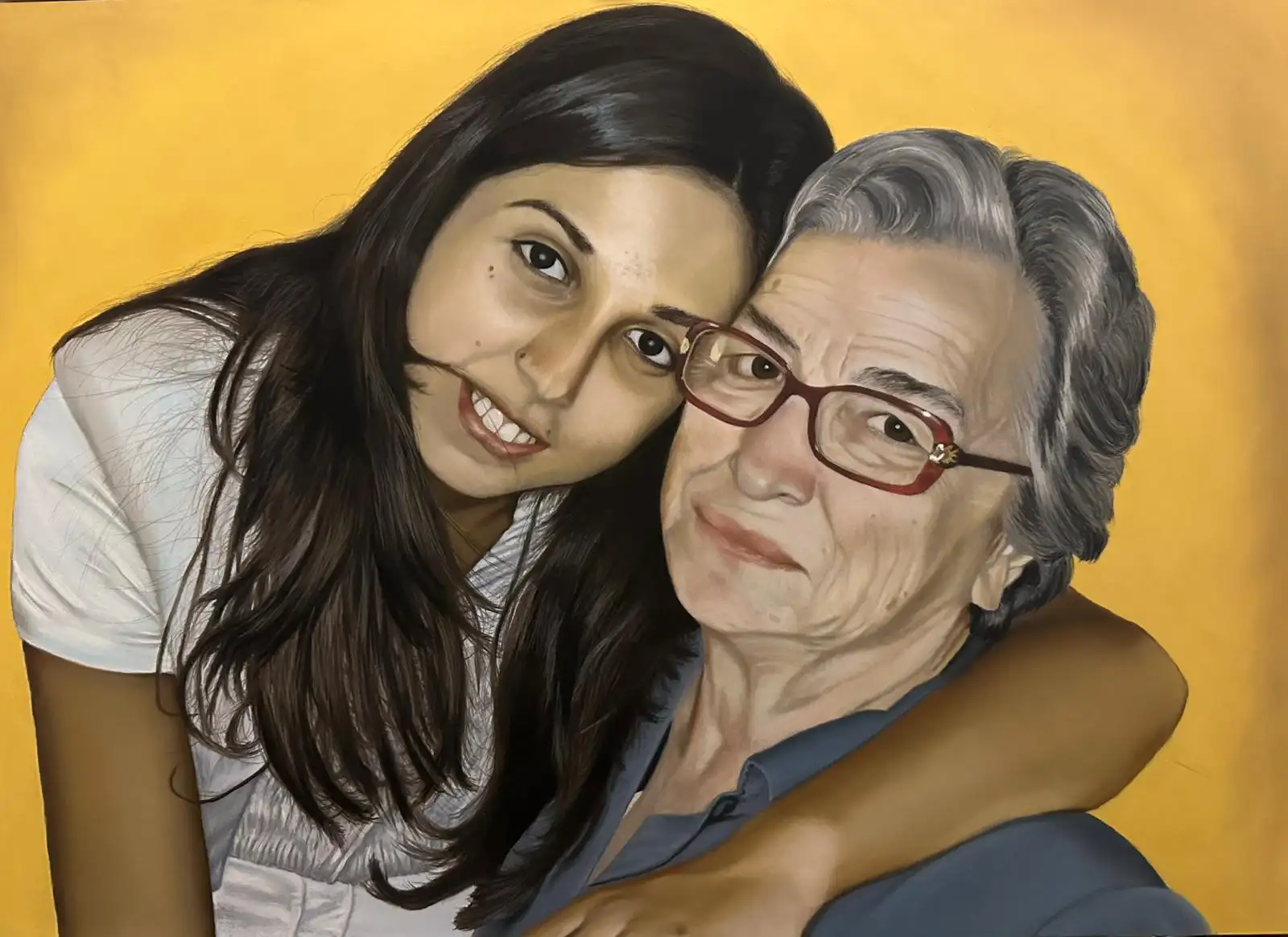 Amore di nonna,La giovane donna, a sinistra, ha lunghi capelli scuri che le incorniciano il viso e un'espressione sorridente e affettuosa, con gli occhi rivolti verso l'osservatore. Indossa una maglietta bianca e il suo braccio destro è amorevolmente avvolto attorno alla spalla dell'anziana. Un dettaglio curioso e sbarazzino è una piccola ciocca di capelli che le sfiora la bocca.